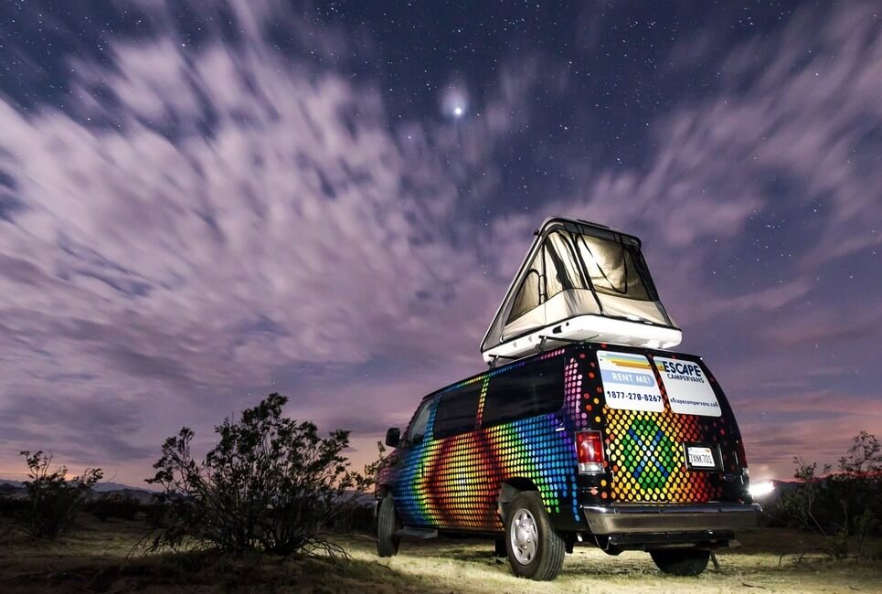 A hardshell James Baround rooftop tent on a campervan at night
