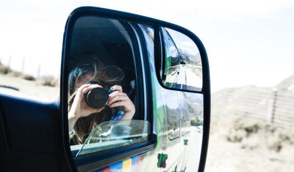 A woman taking a photo with her camera on a road trip with Escape Camper Vans