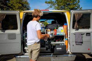 A young man cooking in a campervan kitchen