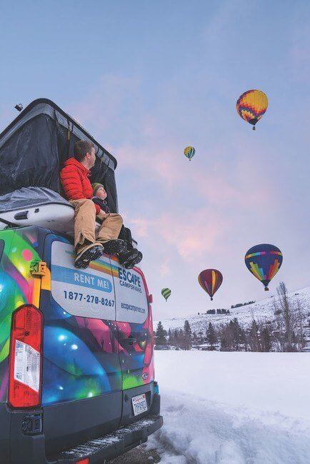 Family watching balloon festival from campervan.