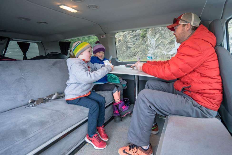 Family playing card game in back of campervan.