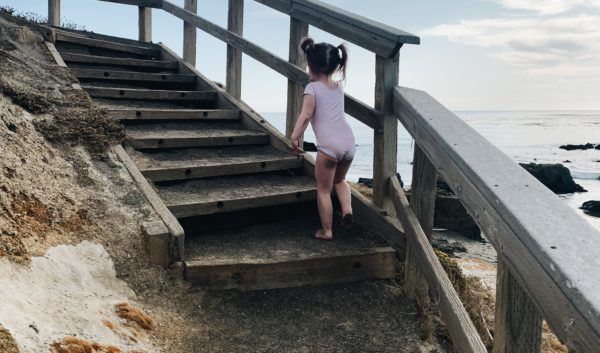 Toddler scaling the stairs at Pebble Beach