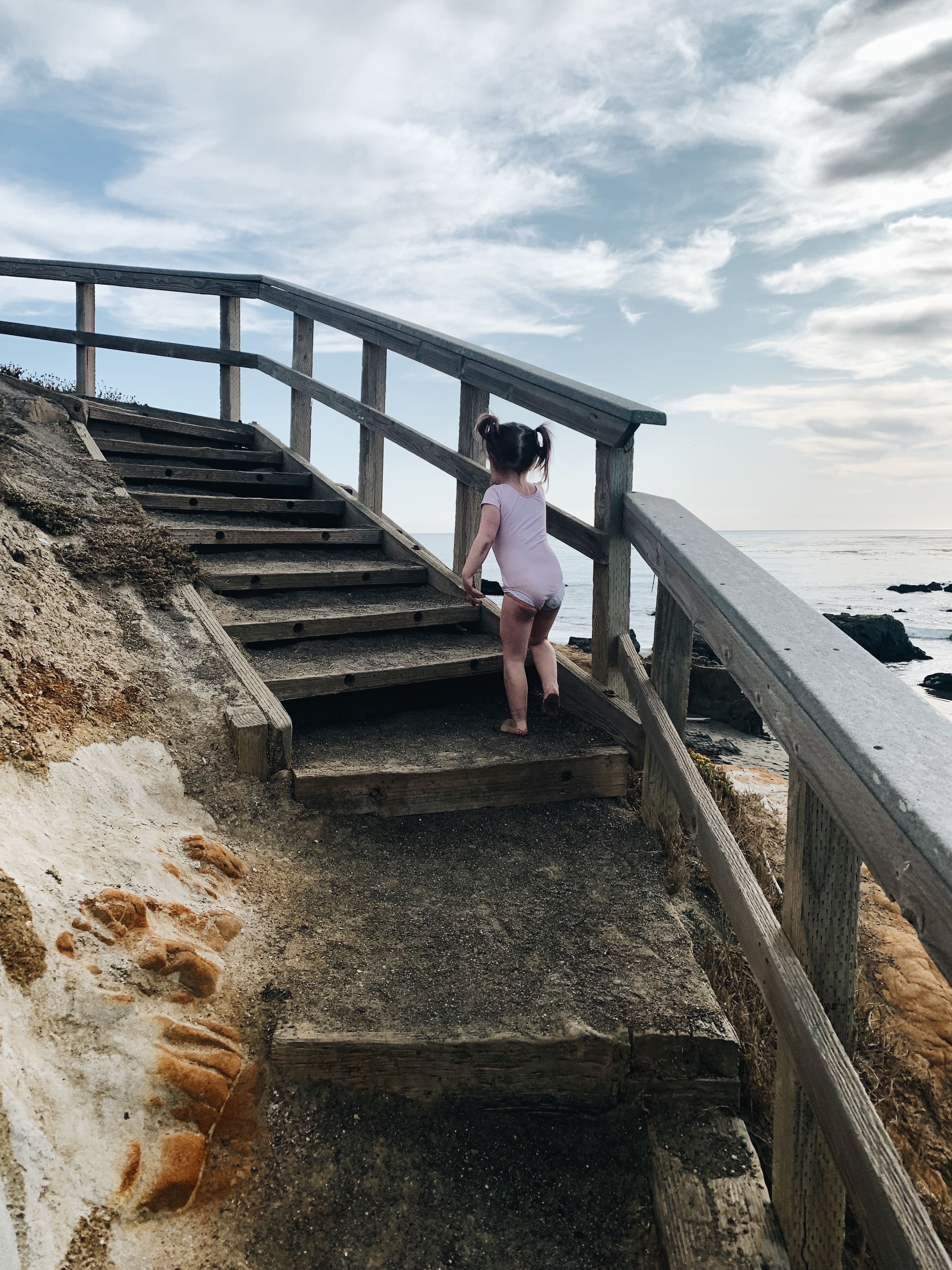 Toddler scaling the stairs at Pebble Beach