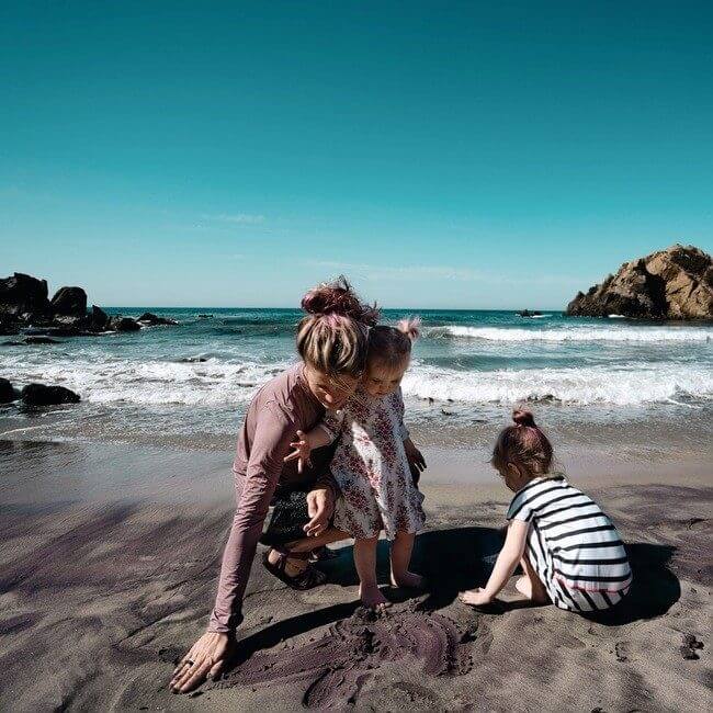 Family playing in the purple sand on Pfieffer Beach