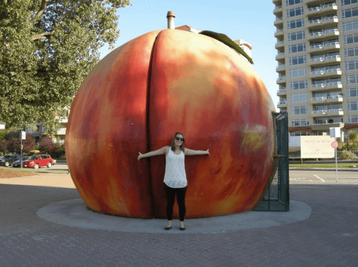 Woman standing in front of a giant peach in Peachland