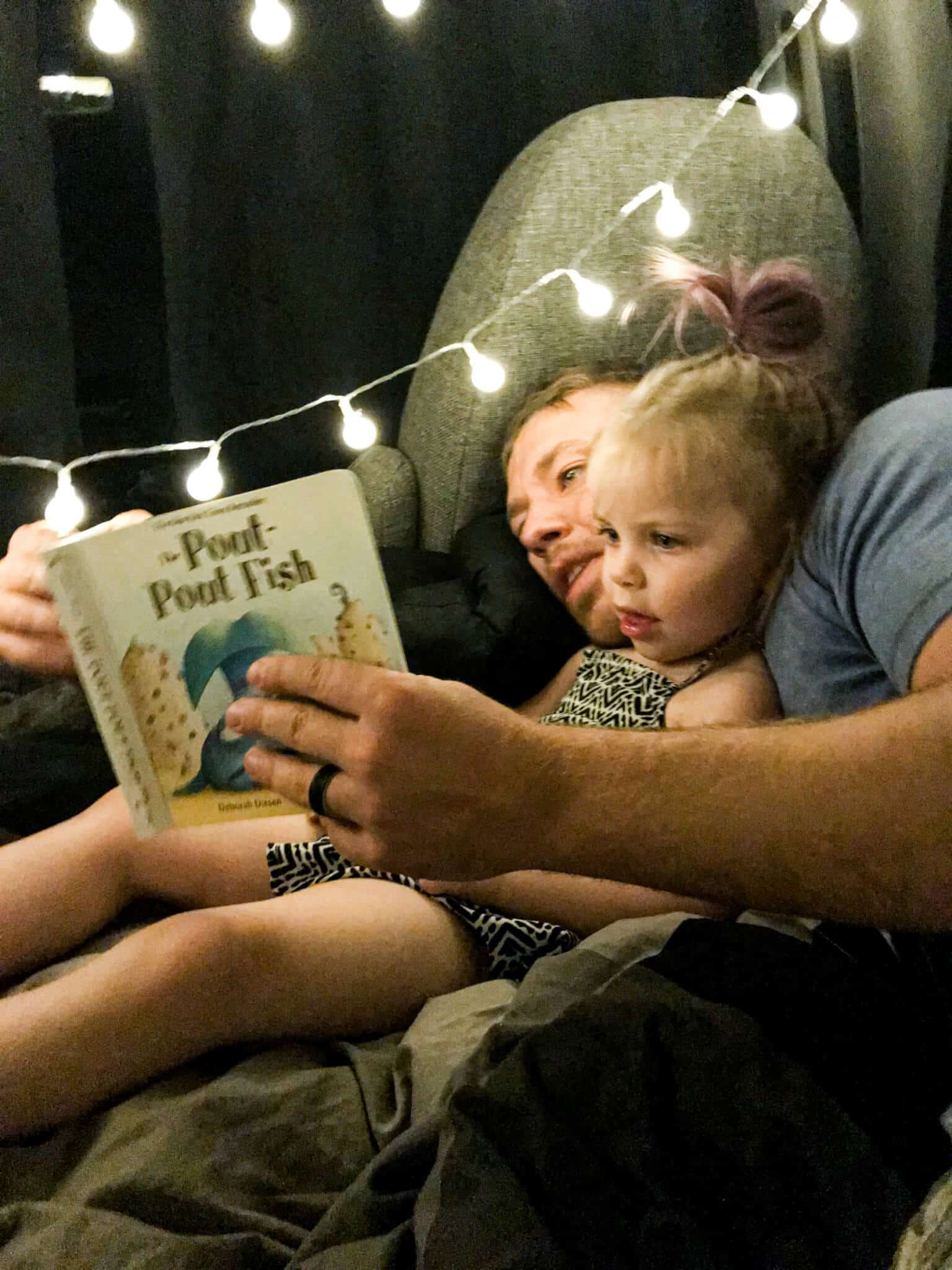 Dad reading to child in the back of a campervan
