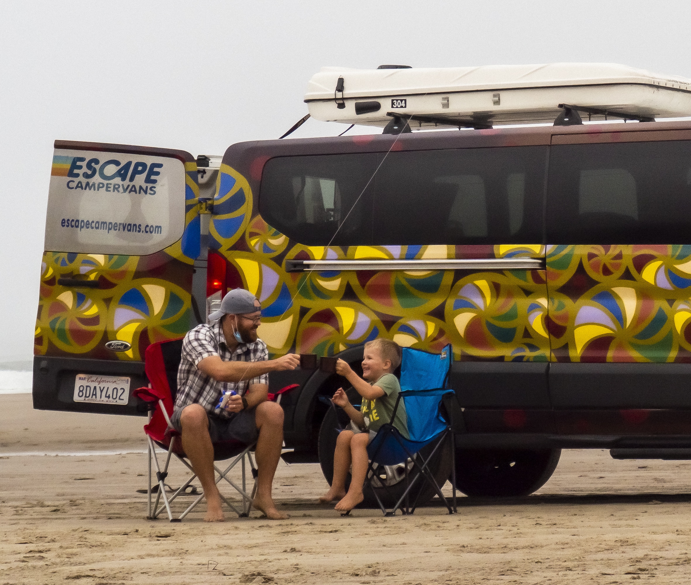 Father and son sitting next to an Escape Campervan