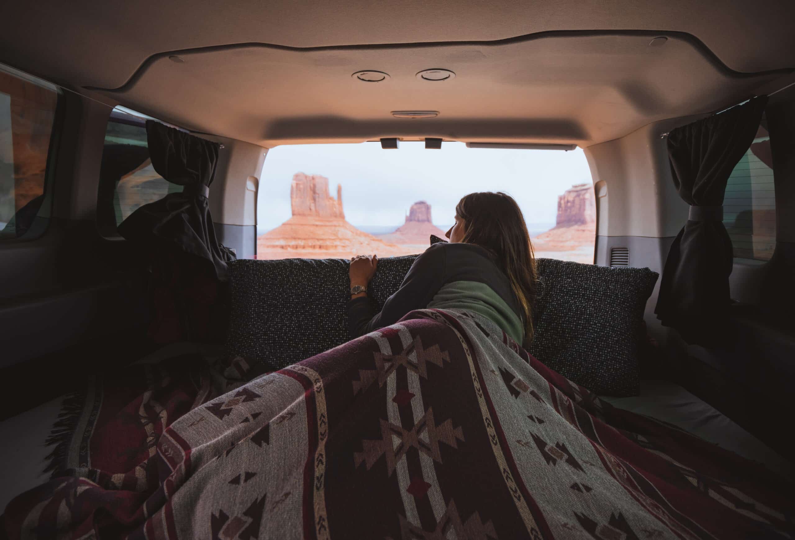 Woman sitting in a camper van bed traveling from Phoenix to Monument Valley.