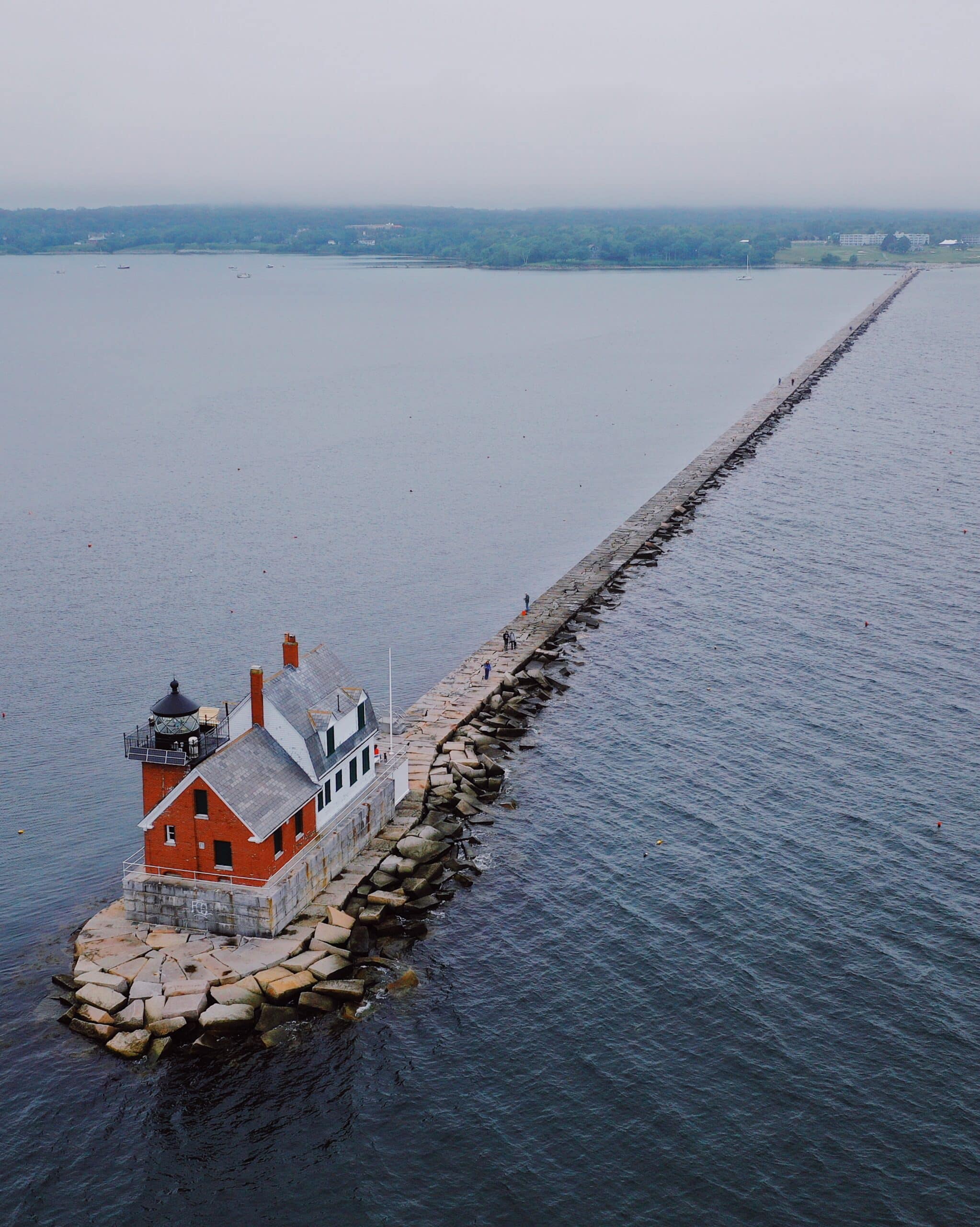 Drone shot of a lighthouse on a pier off the New England coast taken on an Escape Camper Van road trip.
