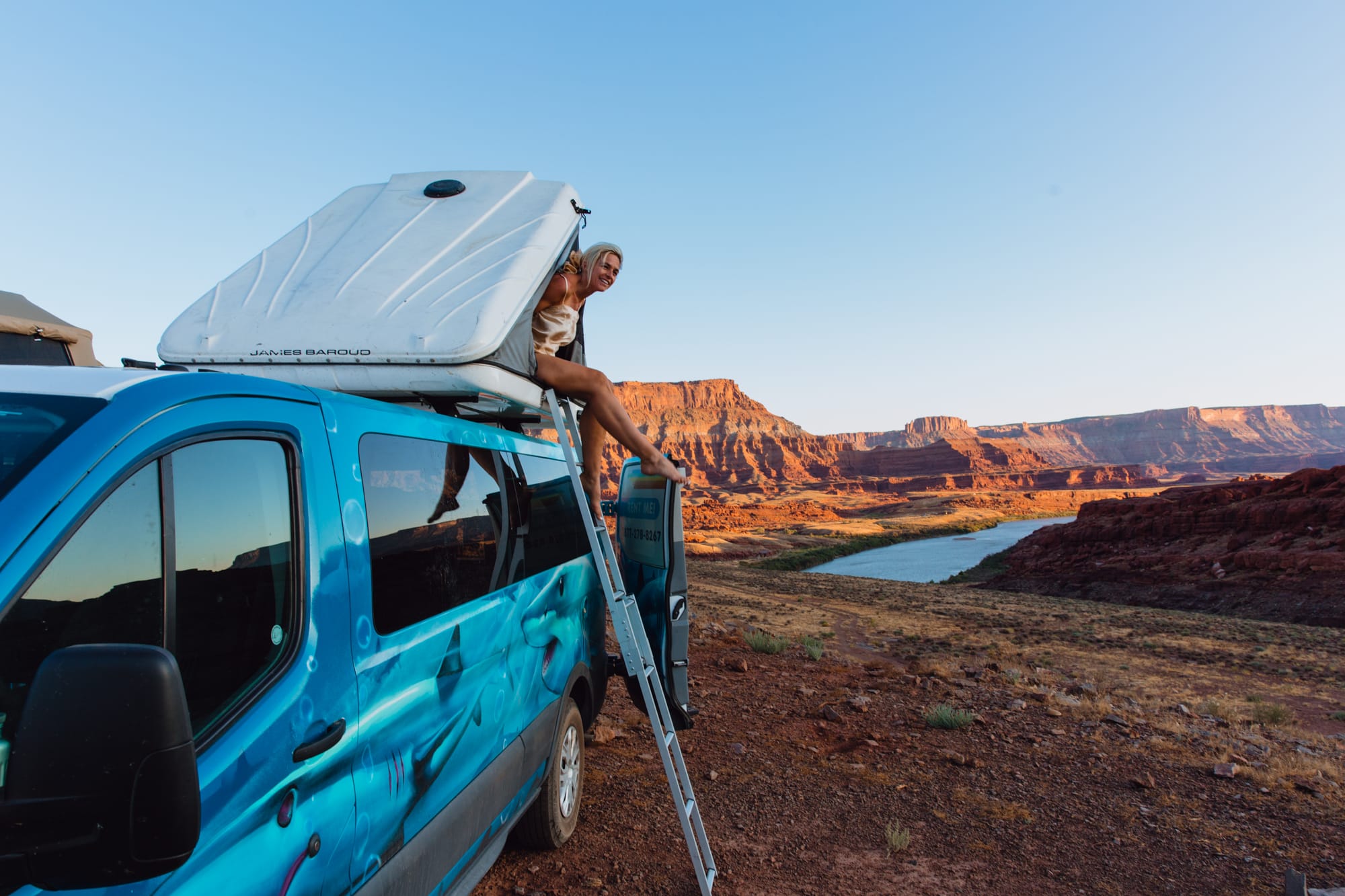 Person sitting in a rooftop tent in an Escape Camper Van rental outside out Capitol Reef Utah
