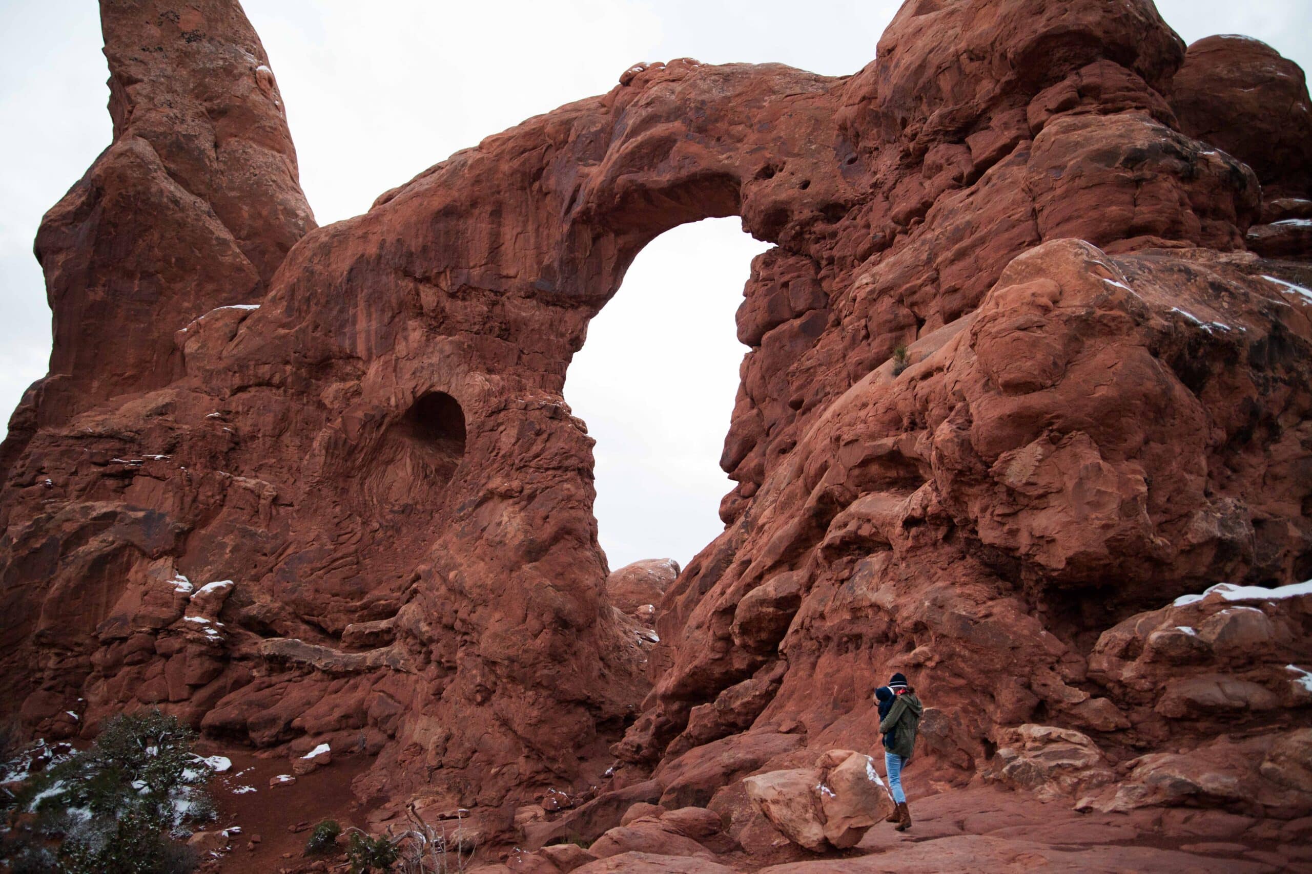 A woman standing under an arch in Arches National Park in Utah.