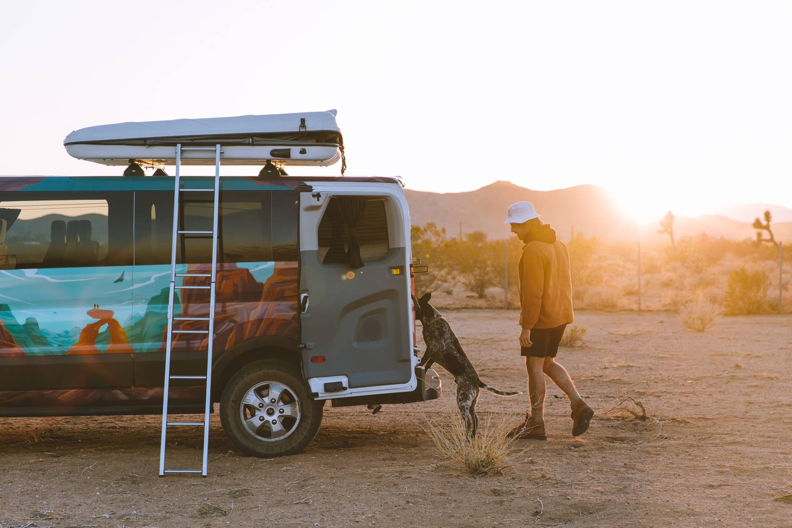 A man and his dog jumping into an Escape Camper Van in Joshua Tree National Park.